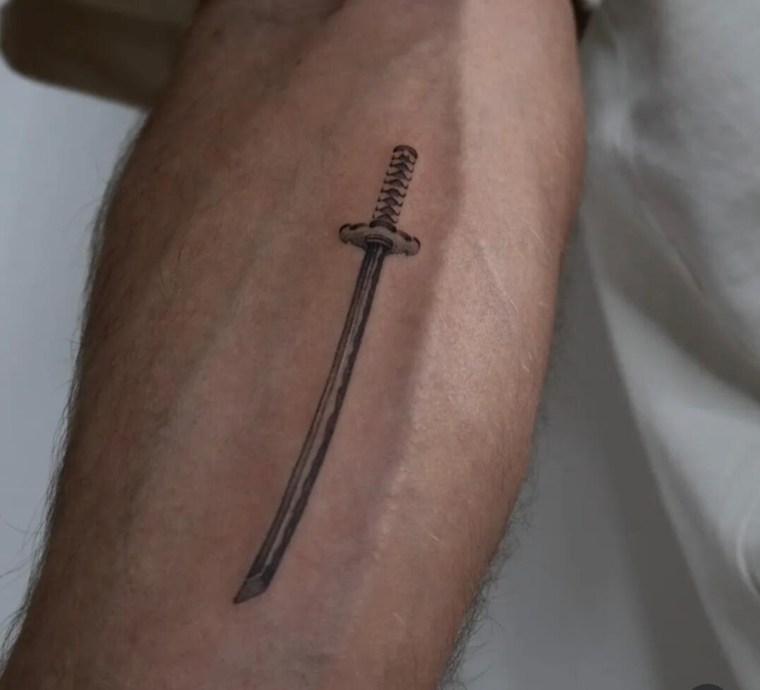 Fineline sword on arm tattoo